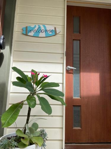 a door to a house with a plant next to it at Little Whale House in Mudjimba