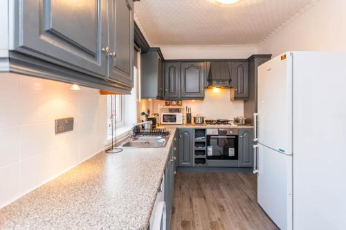 a kitchen with gray cabinets and a white refrigerator at Two Bed Entire House Newcastle Gateshead - Free Parking in Sheriff Hill