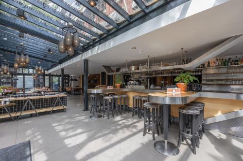 eine Bar mit Hockern und Tischen in einem Restaurant in der Unterkunft Boutique Hotel Corona in Den Haag