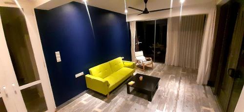 un sofá amarillo en una sala de estar con una pared azul en Marino Mirissa, en Mirissa