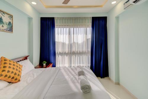 a bedroom with a large bed with blue curtains at Premium 2BHK apartment with Pool Access in Vasco Da Gama