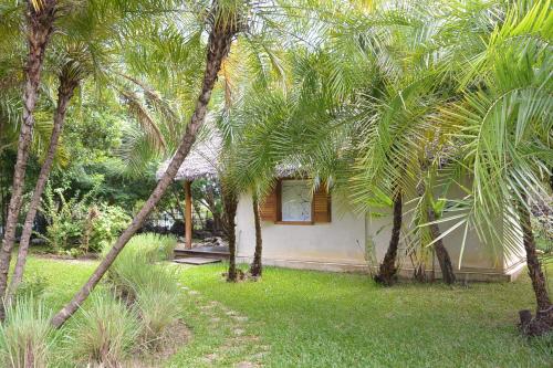 a small house with palm trees in a yard at Coco Komba Lodge in Nosy Komba