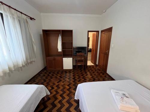 a hotel room with two beds and a desk at Acomodare Hotel in Tubarão