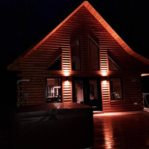a house with lights on the front of it at night at Islander Lodge - Lochaber Lake Lodges in Antigonish