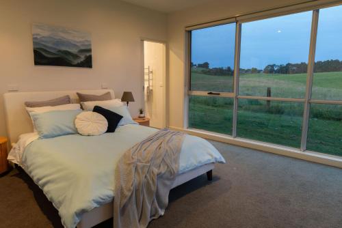 sypialnia z dużym łóżkiem i dużym oknem w obiekcie Tall Trees Country Escape w mieście Foster