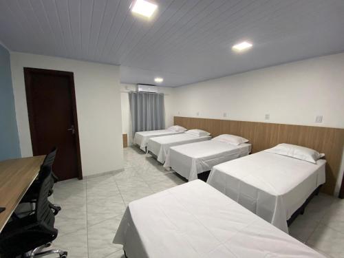 a room with a row of beds in it at Pousada Route 58 in Gravataí