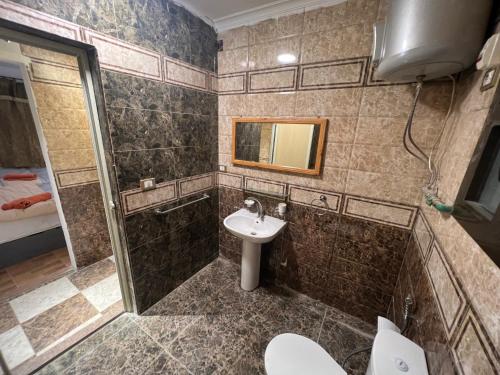 een badkamer met een wastafel, een toilet en een spiegel bij NEAR THE PYRAMIDS Inn in Caïro