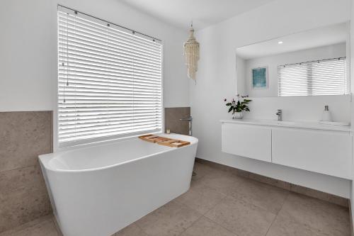a white bathroom with a tub and a sink at Seaglass - Karikari Peninsula Holiday Home in Kaitaia
