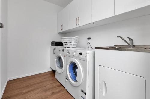 a white laundry room with a washing machine and a sink at Seaglass - Karikari Peninsula Holiday Home in Kaitaia