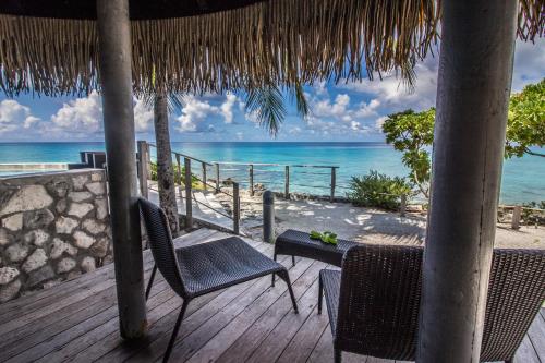 a deck with chairs and a table and the ocean at Maitai Rangiroa in Avatoru