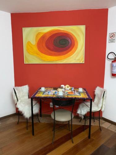 una mesa con sillas en una habitación con una pintura en Hotel e Spa Provençal, en Canela