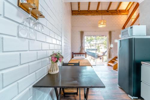 a kitchen with a table and a refrigerator at Pousada Hanalie in Praia do Rosa