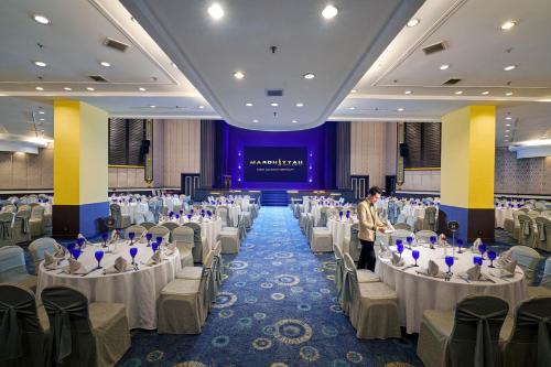a banquet hall with tables and chairs and a man standing in the middle at Mardhiyyah Hotel and Suites in Shah Alam