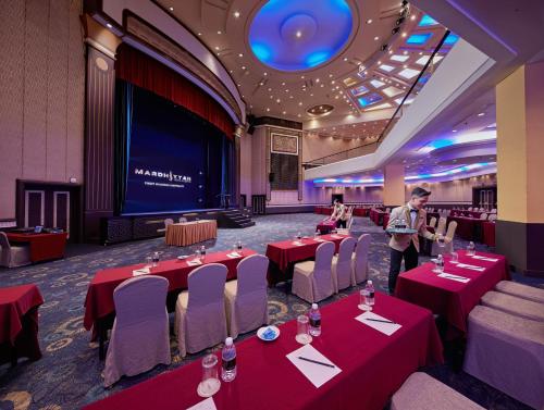 a man standing in a banquet room with red tables and chairs at Mardhiyyah Hotel and Suites in Shah Alam