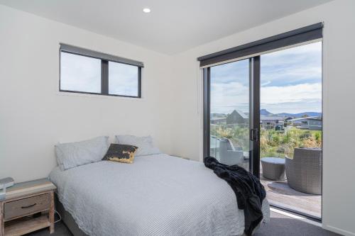 a bedroom with a bed and a large window at Hosts on the Coast - Leighs' Luxury Retreat in Cooks Beach