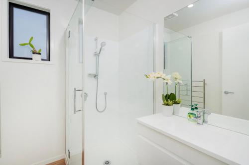 a white bathroom with a shower and a sink at Hosts on the Coast - Leighs' Luxury Retreat in Cooks Beach