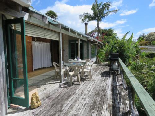a deck with a table and chairs and a grill at Mill Bay Charmer in Mangonui