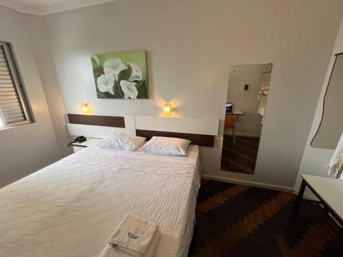 a bedroom with a large white bed and a mirror at Oscar Palace Hotel - SOB NOVA GESTÃO in Tubarão