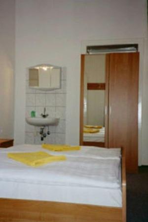 - une chambre avec un lit, un lavabo et un miroir dans l'établissement Pension Wedding, à Berlin