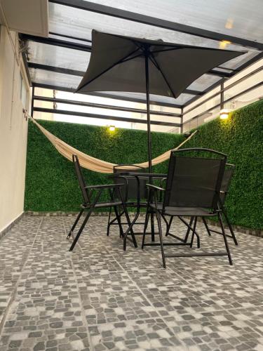 a patio with a hammock and two chairs and an umbrella at Departamento Ecoface Vallarta in Puerto Vallarta