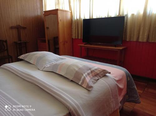 a bed with a pillow and a flat screen tv at Hospedaje Colonial Tarmeño. in Tarma