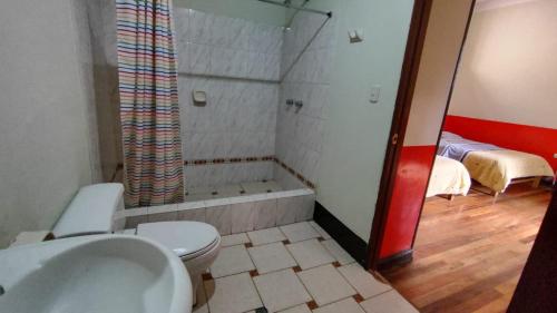 y baño con ducha, aseo y bañera. en Hospedaje Colonial Tarmeño., en Tarma