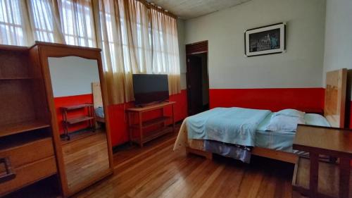 a bedroom with a bed and a television at Hospedaje Colonial Tarmeño. in Tarma