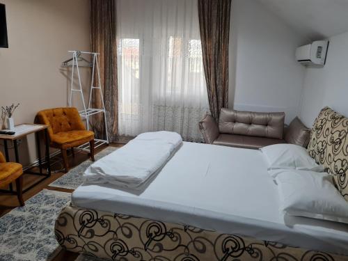 a bedroom with a bed and a couch and a chair at Pensiunea Clasic in Gherla