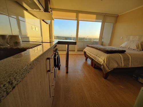 a bedroom with a bed and a kitchen with a counter at Depto Full Equipado en Centro de Chillán con Estacionamiento 10 in Chillán