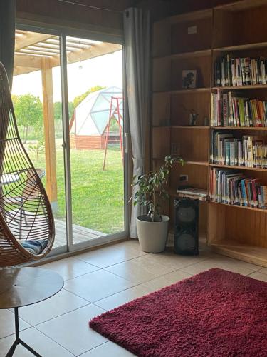 una sala de estar con una silla y una estantería con libros en Casa El Arrebol, sector Saltos del Laja, en Cabrero