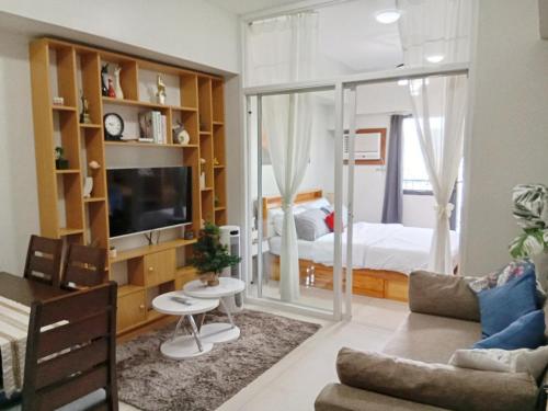 a living room with a television and a bedroom at 1 bedroom condo unit at Sundance Residences in Cebu City