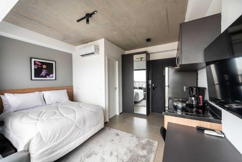 a bedroom with a white bed and a kitchen at Kaza Noah VN Ueno Bela Vista in Sao Paulo