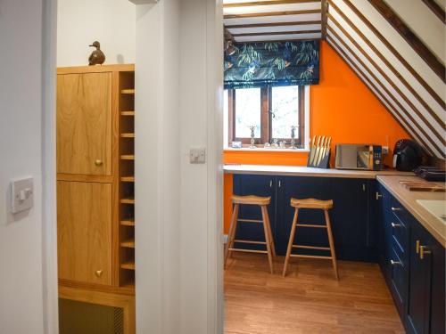 a kitchen with blue cabinets and orange walls at Kingfisher Granary in Ashburnham