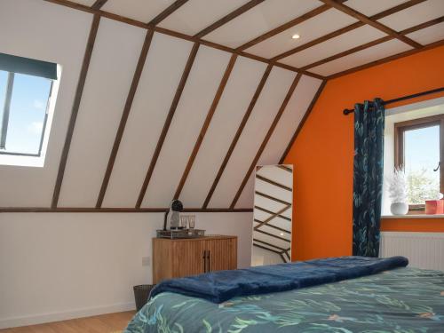 een slaapkamer met een oranje en wit plafond bij Kingfisher Granary in Ashburnham