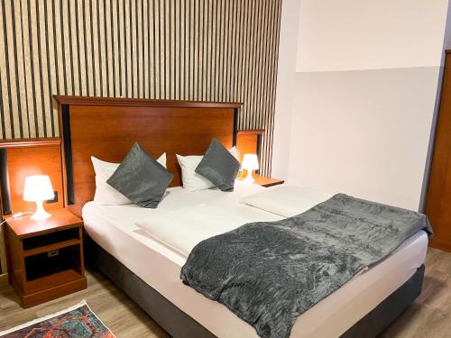 a bedroom with a large bed with two lamps on it at City Hotel West in Frankfurt