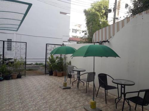 a patio with tables and chairs and green umbrellas at Smart Hostel in Bangkok