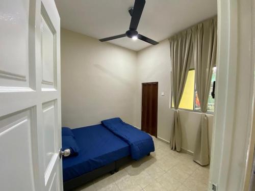 una camera con letto blu e ventilatore a soffitto di BARAKAH HOMESTAY a Kota Tinggi