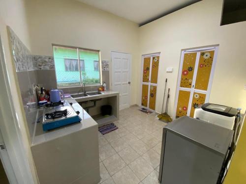 a kitchen with a counter and a sink and a refrigerator at BARAKAH HOMESTAY in Kota Tinggi