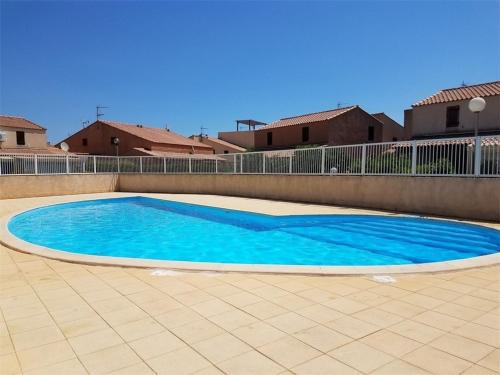 une grande piscine bleue sur un patio carrelé dans l'établissement **Villa 4 pièces pour 7 avec piscine, proche plage, Gruissan** - FR-1-409-90, à Gruissan