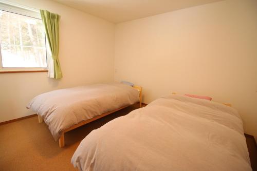 two beds in a room with a window at Cottage All Resort Service / Vacation STAY 8402 in Inawashiro