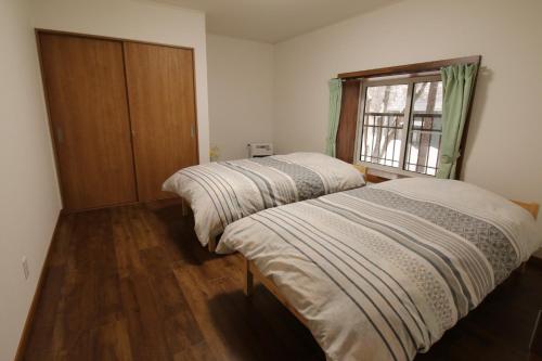 2 Betten in einem Zimmer mit Fenster in der Unterkunft Cottage All Resort Service / Vacation STAY 8410 in Inawashiro
