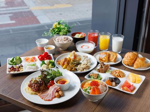a wooden table with plates of food and drinks at Susukino Granbell Hotel in Sapporo