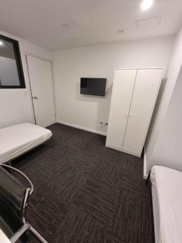 シドニーにあるSydney Airport Guest Houseのベッド1台とテレビが備わる小さな客室です。