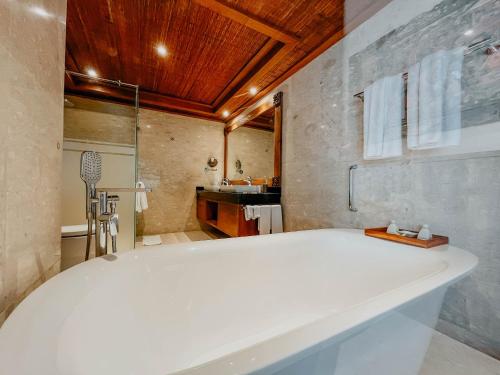a large white tub in a bathroom with a sink at Sakti Garden Resort & Spa in Ubud