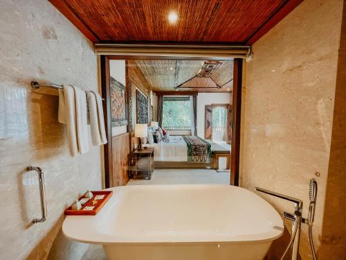 a bathroom with a tub and a bedroom with a bed at Sakti Garden Resort & Spa in Ubud