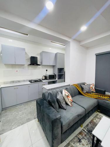 a living room with a couch and a kitchen at AMERICANA LUXURY APARTMENT in Lekki