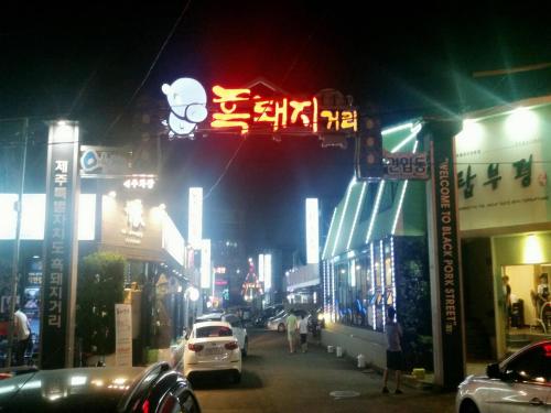 a busy city street at night with signs and cars at Daedong Hotel in Jeju