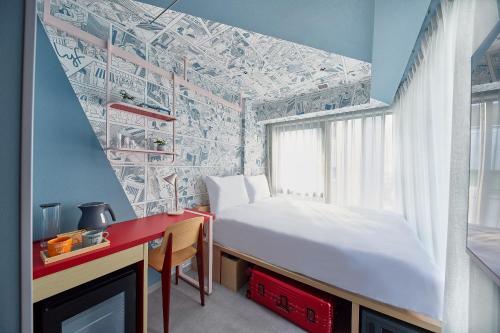 a small bedroom with a bed and a desk and a window at lyf Ginza Tokyo in Tokyo