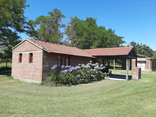 ein kleines Backsteingebäude mit einem Pavillon und Blumen in der Unterkunft Cabañas Sol de las Sierras in Tandil