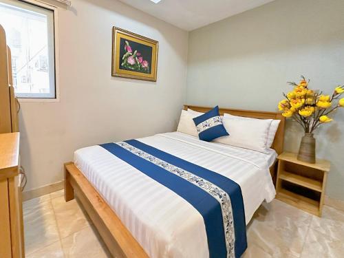 a bedroom with a bed and a vase of flowers at LUAN VU Hotel - Bui Vien Walking Street in Ho Chi Minh City